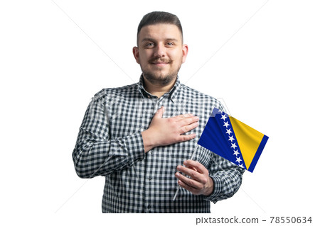 White guy holding a flag of Bosnia and Herzegovina and holds his hand on his heart isolated on a white background With love to Bosnia and Herzegovina 78550634