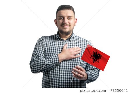 White guy holding a flag of Albania and holds his hand on his heart isolated on a white background With love to Albania White guy holding a flag of Albania and holds his hand on his heart isolated on a white background With love to Albania 78550641