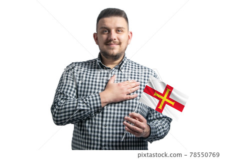 White guy holding a flag of Guernsey and holds his hand on his heart isolated on a white background With love to Guernsey White guy holding a flag of Guernsey and holds his hand on his heart isolated on a white background With love to Guernsey 78550769