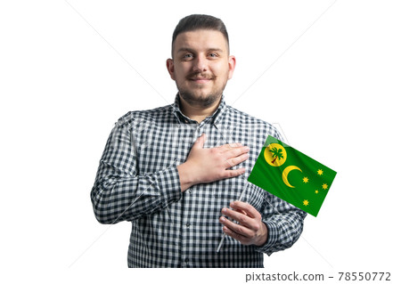 White guy holding a flag of Cocos Islands and holds his hand on his heart isolated on a white background With love to Cocos Islands White guy holding a flag of Cocos Islands and holds his hand on his heart isolated on a white background With love to Cocos Islands 78550772