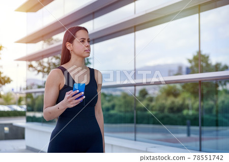 Female model with sportswear and fit body looking at the smart phone Female model with sportswear and fit body looking at the smart phone 78551742