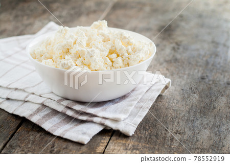 fresh cottage cheese in a white bowl on a wooden background fresh cottage cheese in a white bowl on a wooden background 78552919