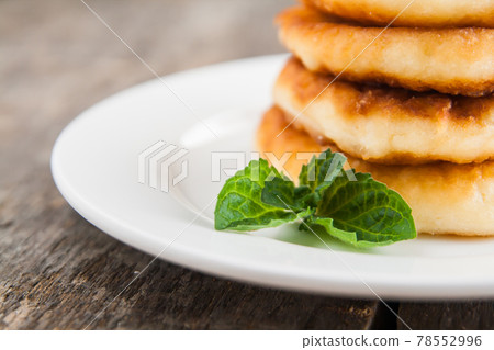 stack of cheesecakes with jam on a white plate on a dark wooden background stack of cheesecakes with jam on a white plate on a dark wooden background 78552996