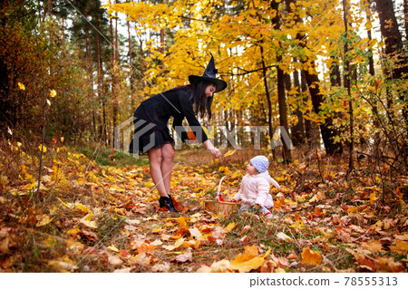 woman witch plays with a small child in the autumn forest. halloween concept costumes. witch and bunny. concept mother and daughter friends woman witch plays with a small child in the autumn forest. halloween concept costumes. witch and bunny. concept mother and daughter friends 78555313