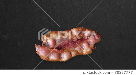 crispy thick cut smoked bacon slices isolated on dark background, close up view suitable for food design project. crispy thick cut smoked bacon slices isolated on dark background, close up view suitable for food design project. 78557777