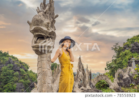 Woman tourist on background of amazing huge dragon statue at limestone mountain top near Hang Mua view point at foggy morning. Popular tourist attraction at Tam Coc, Ninh Binh. Vietnam travel Woman tourist on background of amazing huge dragon statue at limestone mountain top near Hang Mua view point at foggy morning. Popular tourist attraction at Tam Coc, Ninh Binh. Vietnam travel 78558923
