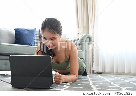 Attractive woman learning new exercises watching online workout tutorials over her computer laptop at home. Attractive woman learning new exercises watching online workout tutorials over her computer laptop at home. 78561822