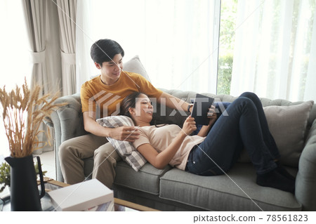 Happy young couple watching online media with a digital tablet having fun together in living room. 78561823
