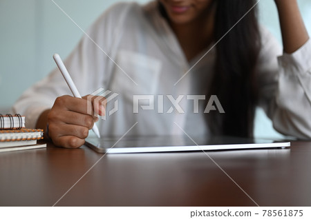 Croped shot of young businesswoman using styluspen writing information on digital tablet in her office. Croped shot of young businesswoman using styluspen writing information on digital tablet in her office. 78561875