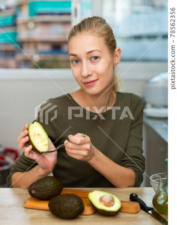 Portrait of girl with avocado in home kitchen 78562356
