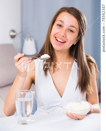 Female teenager is enjoying tasty curd Female teenager is enjoying tasty curd 78562387