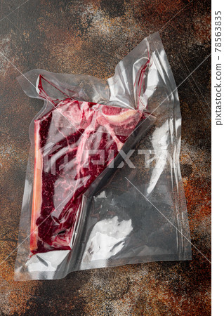 Raw beef steak t-bone or porterhouse in vacuum Pack, on old dark rustic background, top view flat lay Raw beef steak t-bone or porterhouse in vacuum Pack, on old dark rustic background, top view flat lay 78563835