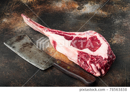 Raw fresh tomahawk dry aged marbled beef chop steak, and old butcher cleaver knife, on old dark rustic background, with copy space for text 78563838