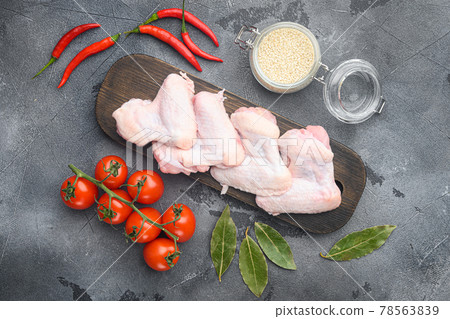 Fresh raw middle chicken wings with ingredients, and sesame, on wooden cutting board, on gray background, top view flat lay Fresh raw middle chicken wings with ingredients, and sesame, on wooden cutting board, on gray background, top view flat lay 78563839