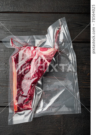 Raw beef steak t-bone or porterhouse in vacuum Pack, on black wooden background, top view flat lay Raw beef steak t-bone or porterhouse in vacuum Pack, on black wooden background, top view flat lay 78564025