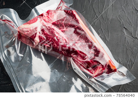 Raw beef steak t-bone or porterhouse in vacuum Pack, on black stone background Raw beef steak t-bone or porterhouse in vacuum Pack, on black stone background 78564040