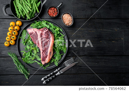 Italian Florentine T-bone beef meat Steak with herbs, on black wooden table background, top view flat lay, with copy space for text 78564062