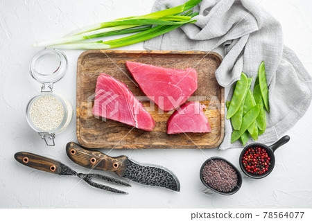 Raw tuna fillet. Seafood with sugar green pea, sesame and ingredients, on wooden tray, on white stone background, top view flat lay Raw tuna fillet. Seafood with sugar green pea, sesame and ingredients, on wooden tray, on white stone background, top view flat lay 78564077