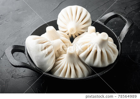 Uncooked Baozi chinese dumplings. Azian dumplings, in frying cast iron pan, on black stone background 78564989