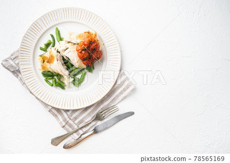 Stuffed chicken meat with filo, with baked cherry tomatoes And green beans, on white stone background, top view flat lay, with copy space for text 78565169