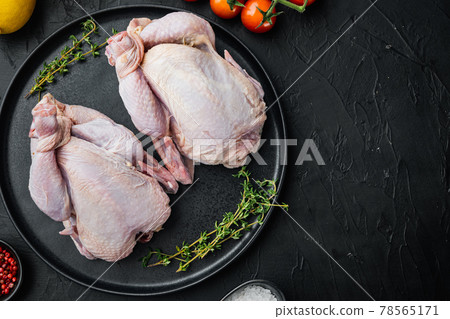 Raw coquelet chickens with herbs spices ingredients, on black background, top view with copy space for text 78565171