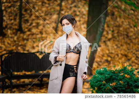 Fashion portrait of sexy woman in face mask and bodysuit in autumn park. Pandemic, coronavirus Fashion portrait of sexy woman in face mask and bodysuit in autumn park. Pandemic, coronavirus 78565486