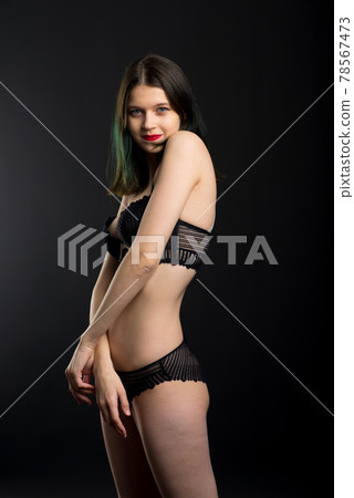 Vertical view photo beautiful shy lady in lace bikini boudoir bra panties. Tender skinny slim shape isolated black background. 78567473