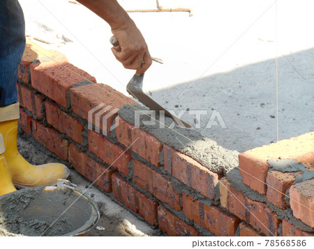 JOHOR, MALAYSIA -NOVEMBER 25, 2016: Bricklayer lay clay bricks block to form building walls at the construction site. JOHOR, MALAYSIA -NOVEMBER 25, 2016: Bricklayer lay clay bricks block to form building walls at the construction site. 78568586