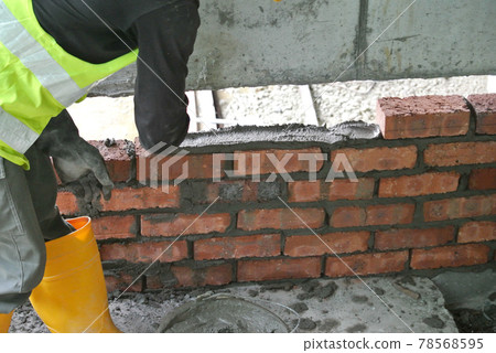 JOHOR, MALAYSIA -NOVEMBER 25, 2016: Bricklayer lay clay bricks block to form building walls at the construction site. JOHOR, MALAYSIA -NOVEMBER 25, 2016: Bricklayer lay clay bricks block to form building walls at the construction site. 78568595