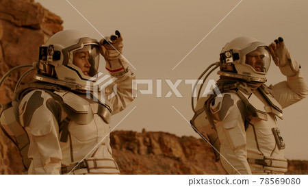 Male and female cosmonauts looking around Male and female cosmonauts looking around 78569080