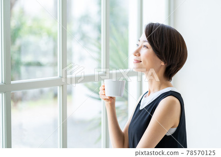在窗口的婦女飲用的咖啡 78570125