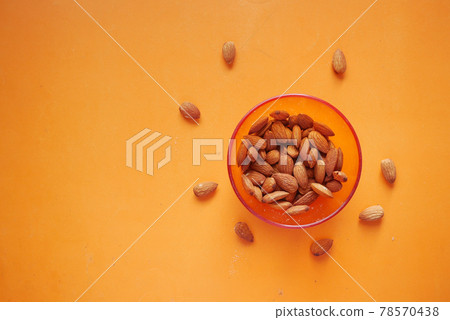 top view of almond nuts in a bowl on orange background top view of almond nuts in a bowl on orange background 78570438