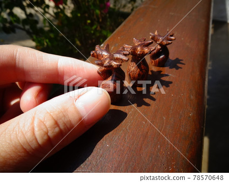 [Madagascar] Baobab Close-up of hands lining up three small wooden figurines of wood (Morondava) 78570648