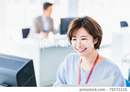 A young business woman using a computer in a bright office A young business woman using a computer in a bright office 78572228