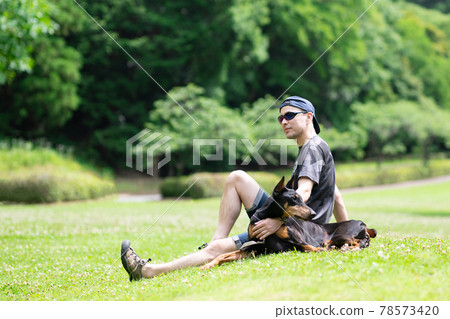 杜賓與一個男人在草坪上放鬆 78573420