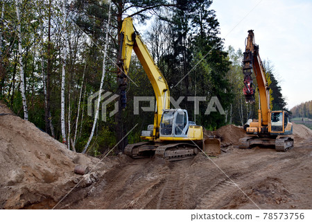 Excavator with drilling attachments at construction site. Excavator with drilling attachments at construction site. 78573756
