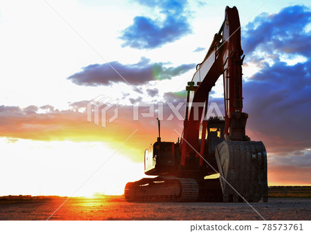 Excavator working on earthmoving at open pit mining on amazing sunset background.  78573761