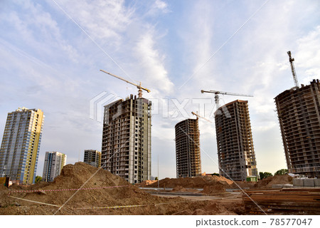 Tower cranes in action at construction site. Construction process of modern residential buildings. Tower cranes in action at construction site. Construction process of modern residential buildings. 78577047