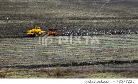 Photo of a tractor working in a field in spring 78577223