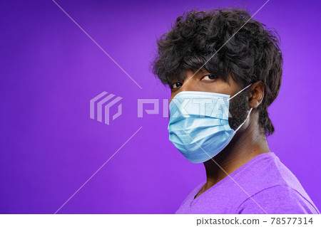 African american man wearing medical face mask against purple background African american man wearing medical face mask against purple background 78577314