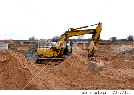 Excavator digs dirt during roadwork at construction site. Heavy machinery and earth-moving equipment Excavator digs dirt during roadwork at construction site. Heavy machinery and earth-moving equipment 78577392