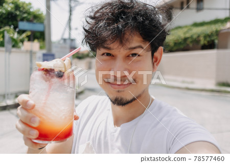 Happy funky hair man drinks Italian soda syrup in hot sunny street of summer. Happy funky hair man drinks Italian soda syrup in hot sunny street of summer. 78577460