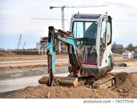 Mini excavator digg trench to lay cables concrete curbs and paving slabs at construction site. 78577556