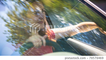 Motion blured image of happy young woman driving a car on a summer road trip travel vacations. Shot trough windshield. Motion blured image of happy young woman driving a car on a summer road trip travel vacations. Shot trough windshield. 78578469