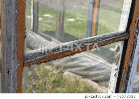 An old greenhouse of rotten windows with cracked paint 78578588