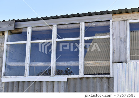 An old greenhouse of rotten windows with cracked paint 78578595