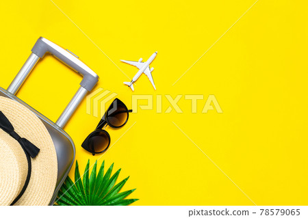 Summer background beach. Suitcase, sunglasses with palm leaves and straw hat, white plane in travel composition on yellow background. Tranquil beach scene with copy space. Summer background beach. Suitcase, sunglasses with palm leaves and straw hat, white plane in travel composition on yellow background. Tranquil beach scene with copy space. 78579065