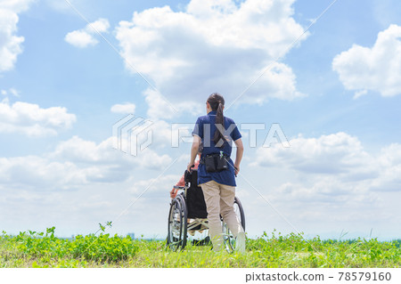 A caregiver pushing a wheelchair A caregiver pushing a wheelchair 78579160