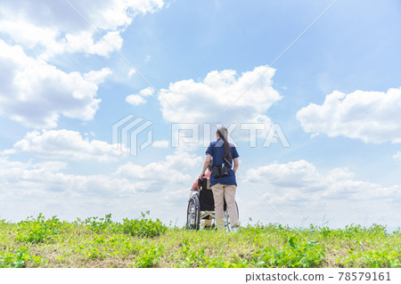 A caregiver pushing a wheelchair A caregiver pushing a wheelchair 78579161