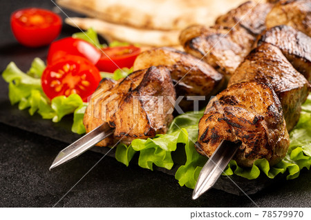 Two portions of shish kebab on a stone plate with salad. Two portions of shish kebab on a stone plate with salad. 78579970